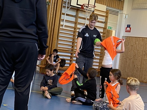 En eftermiddag i veckan möter OV Handboll och Skola lågstadieeleverna på Västra Berga. Jacob Andersson delar ut västar.