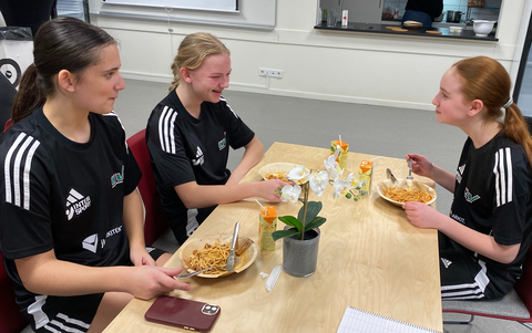Kolhydratpåfyllning inför eftermiddagspassen. Abby Frigell-De Simone, Amanda Glenzer och Martha Andersson laddar om.